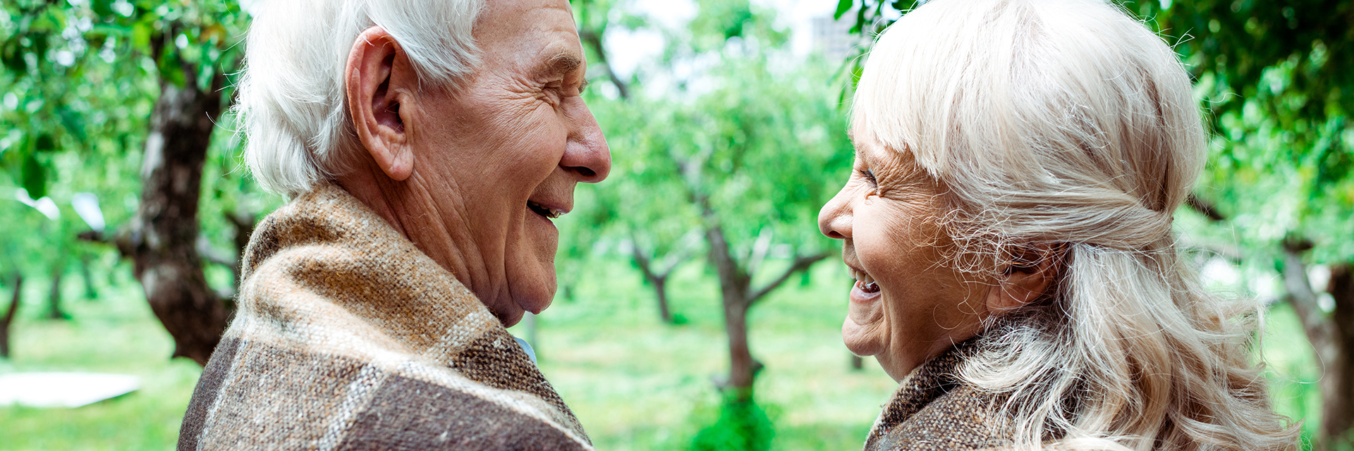head shot of senior couple smiling at each other outside